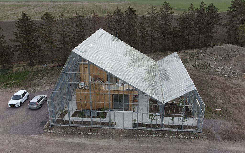 Asymetrisk glasbygning omkring hus